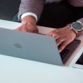 אדם עובד על מחשב MacBook לצד טאבלט וטלפון