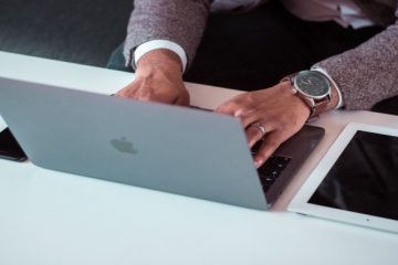 אדם עובד על מחשב MacBook לצד טאבלט וטלפון
